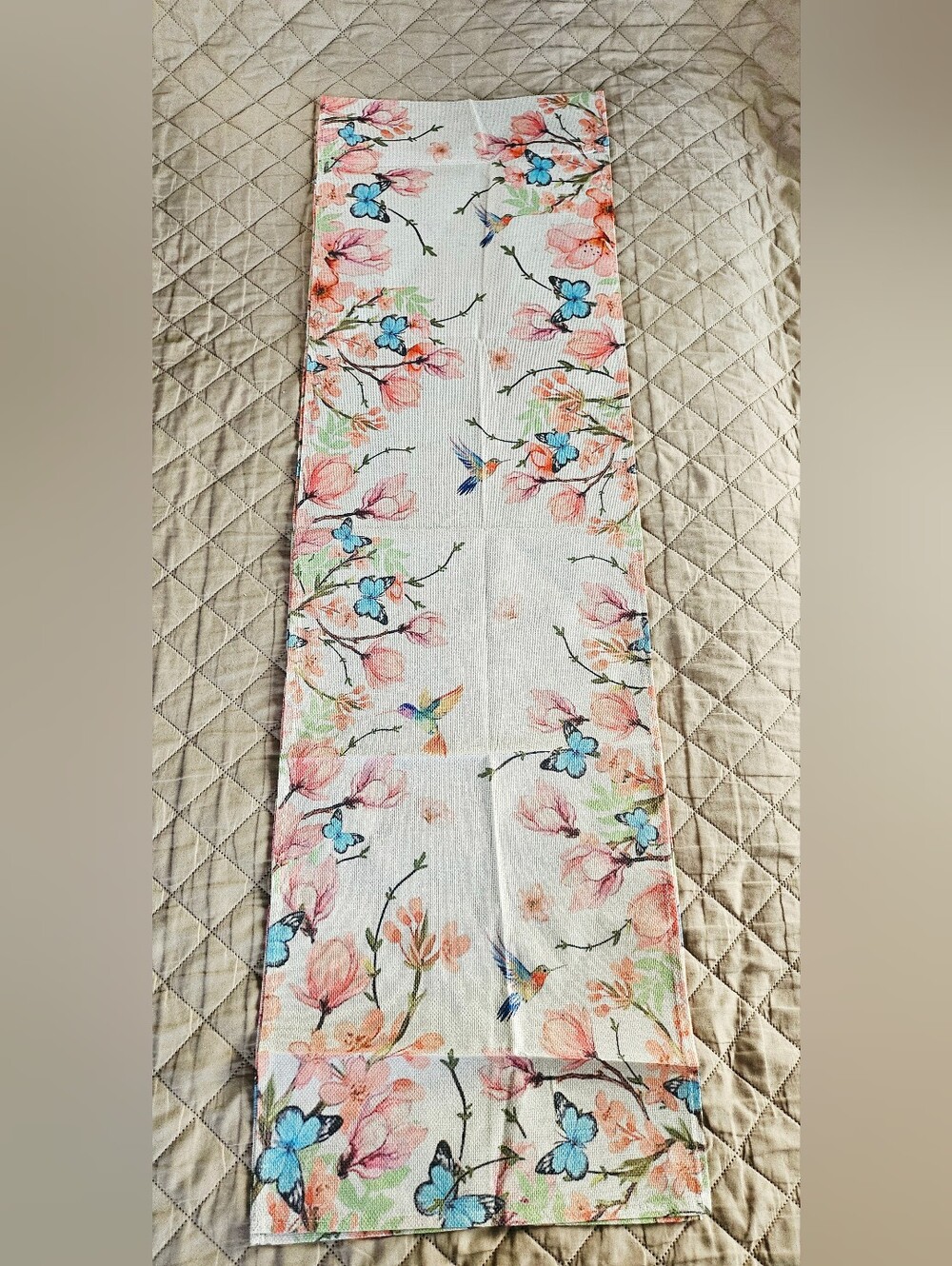 Table runner has pink flowers, hummingbirds, and butterflies.